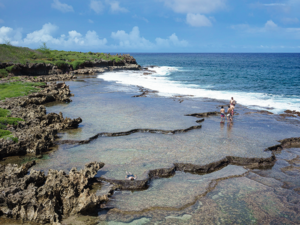 Guam's ocean and sky view from a cliff with people, Inarajan natural pool,